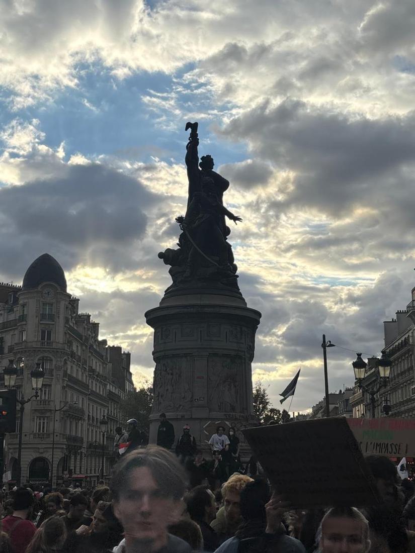 Statue de la place de Clichy sous un ciel d'orage, foule de manifestants