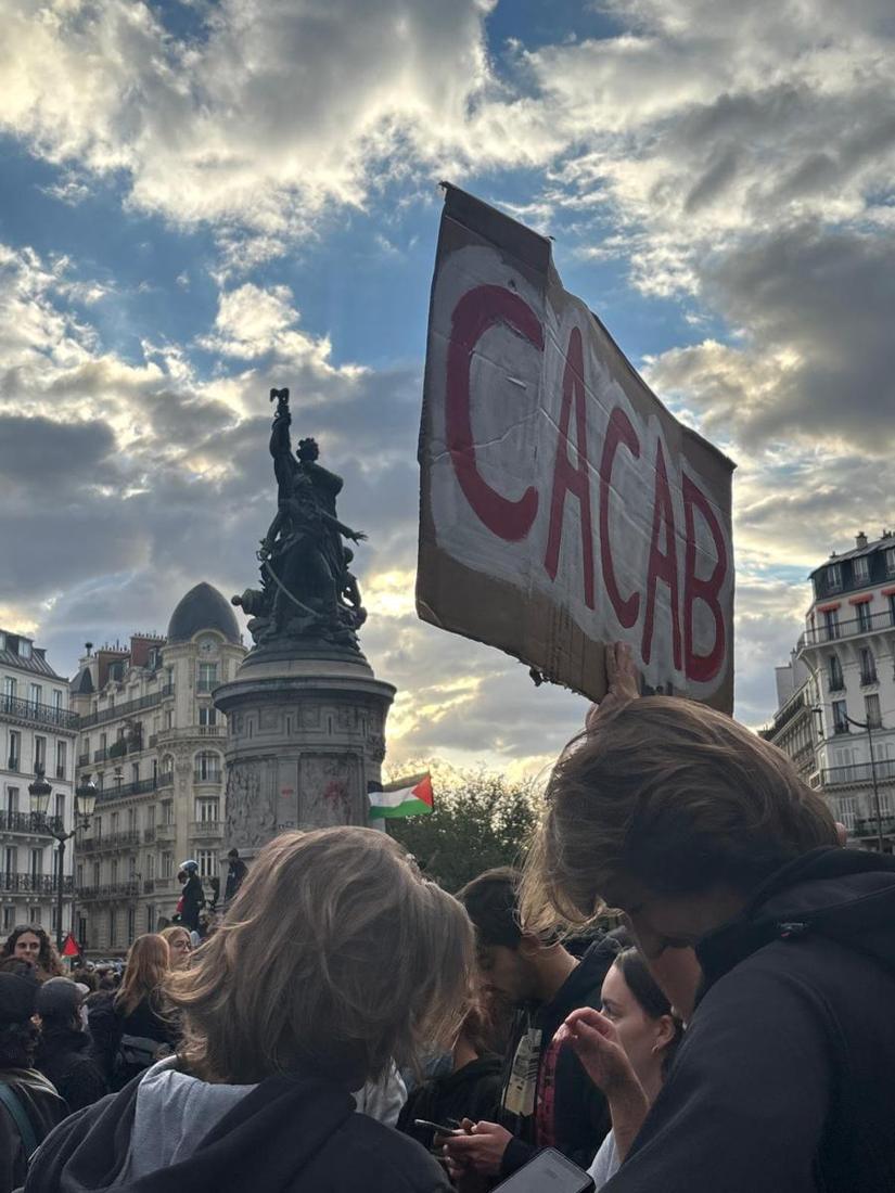 Pancarte levée devant la statue de la place de Clichy