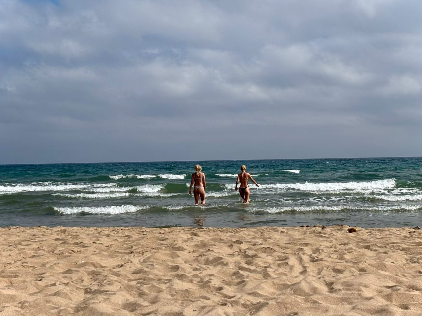 Deux baigneuses entrant dans les vagues sous un ciel gris