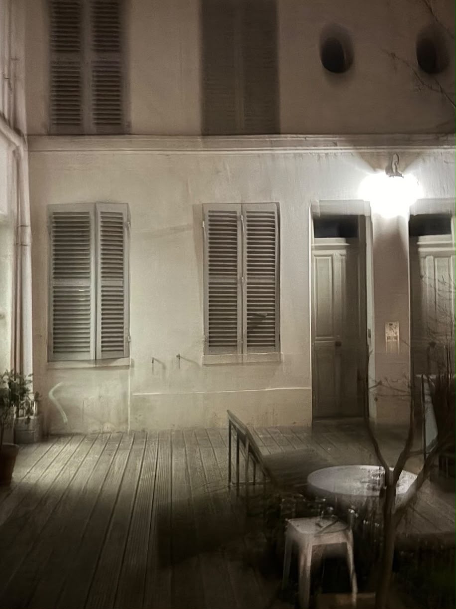 Cour éclairée la nuit, volets clos