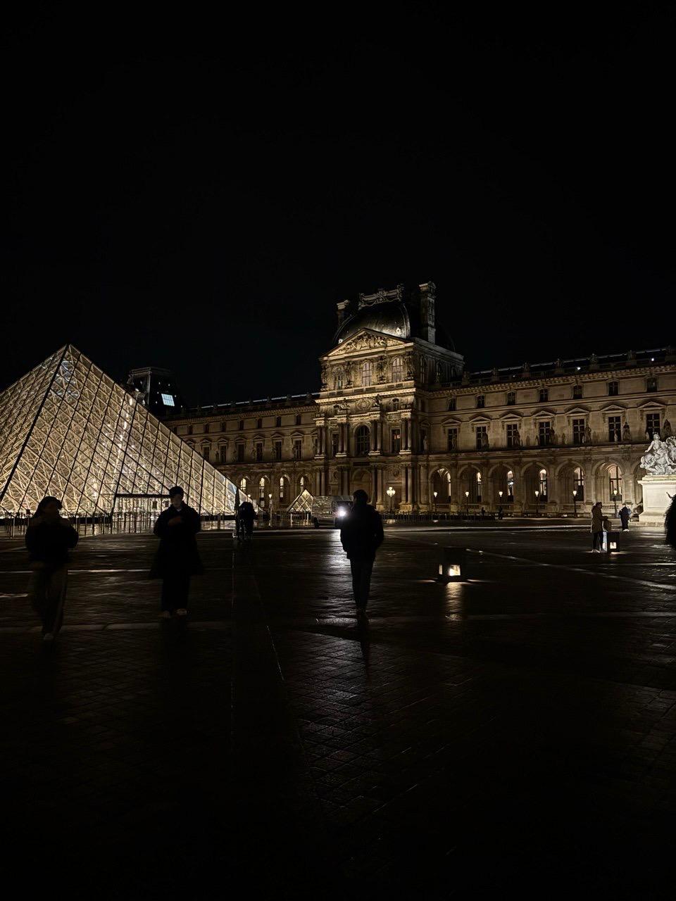 Passants devant la pyramide du Louvre