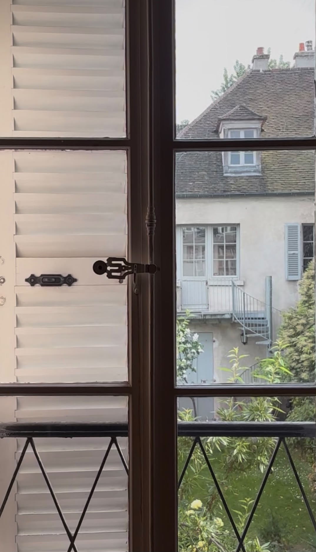 Fenêtre à persiennes ouverte sur un jardin